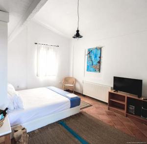 Beach Front Villa in Polychrono في هانيوتي: غرفة نوم مع سرير وتلفزيون بشاشة مسطحة