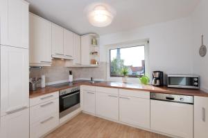 a white kitchen with white cabinets and a window at Glück in der Stadt in Glückstadt