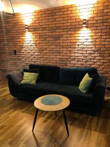 ein schwarzes Sofa mit einem Tisch und einer Ziegelwand in der Unterkunft Studio Rynkowa in Stettin