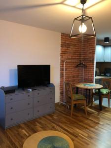 ein Wohnzimmer mit einem TV auf einer Kommode und einem Tisch in der Unterkunft Studio Rynkowa in Stettin