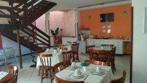a restaurant with tables and chairs and a kitchen at Pousada Arrastão da Ilha in Abraão