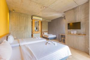 um quarto de hotel com duas camas e uma televisão em EcoLoft Hotel - SHA Plus em Cidade Phuket