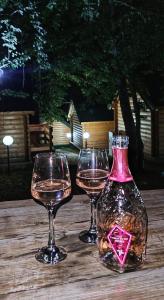 two glasses and a bottle of wine on a wooden table at KOZAK Apartments & Restaurant in Mojkovac +87 photos
