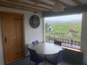 a table and chairs in a room with a large window at Beautiful Thatched Adderwal Cottage Donegal in Doochary
