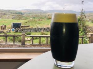 a glass of beer sitting on a table in front of a window at Beautiful Thatched Adderwal Cottage Donegal in Doochary
