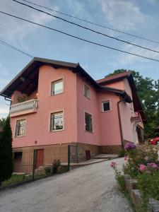 ein rosa Haus mit einem Zaun davor in der Unterkunft Villa Amir in Sarajevo