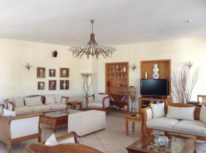 a living room with white furniture and a chandelier at Astir Of Naxos in Naxos Chora