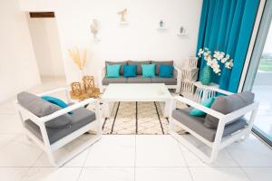 ein Wohnzimmer mit einem Sofa und Stühlen in der Unterkunft Eden Blue vue Mer et Piscine in Sainte-Anne