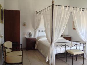 a bedroom with a canopy bed and a chair at Astir Of Naxos in Naxos Chora