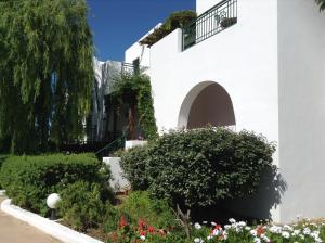 a white building with bushes and flowers at Astir Of Naxos in Naxos Chora