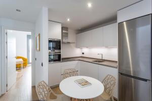 una cocina con armarios blancos y una mesa y sillas blancas. en Private & Pool Goyeneta Sevilla Urban Apartment, en Sevilla