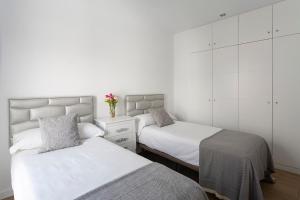 2 camas en un dormitorio con paredes blancas en Private & Pool Goyeneta Sevilla Urban Apartment, en Sevilla