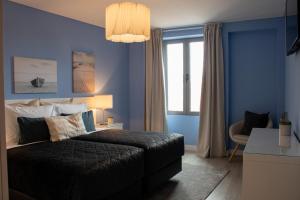 a bedroom with blue walls and a bed and a desk at Kavia Hotel do Largo in Cascais