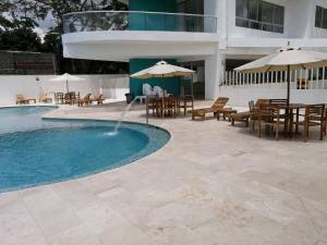una piscina con mesas, sillas y sombrillas en Magico Apartamento Frente al Mar 3 Habitaciones FB73, en Coveñas
