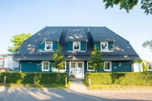 ein blaues Haus mit schwarzem Dach in der Unterkunft ILEX Appartements in Born