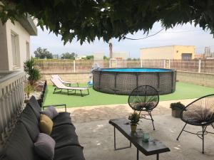 patio con sofá, sillas y piscina en La Caseta del Padri, en Deltebre