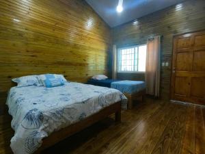 a bedroom with two beds and a wooden wall at Hospedaje Yarisnori in Bocas Town