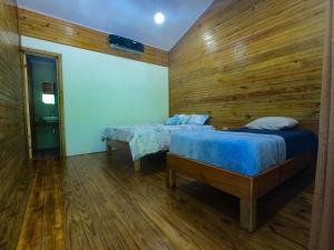 a bedroom with two beds and a wooden wall at Hospedaje Yarisnori in Bocas Town