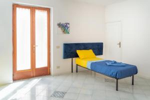 een slaapkamer met een bed met een blauw en geel kussen bij Margherita House in Procida