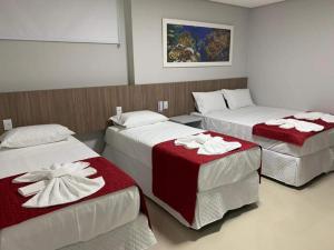 a room with three beds with red and white blankets at Summit Pousada Noah in Maceió