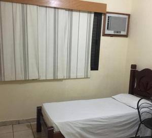 a bedroom with a bed and a window with a tv at OYO Center Hotel, Ribeirão Preto in Ribeirão Preto