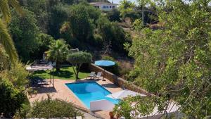 a swimming pool with two umbrellas and a house at Montinho Boutique Studio in Benagil