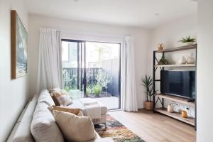 a living room with a couch and a tv at Huntington Townhouse with Patio and Parking in Auckland