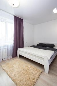 1 dormitorio con cama blanca y alfombra en Центр. Вулиця Руська. 2 кімнати, en Ternopilʼ