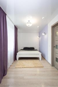 Habitación blanca con cama y alfombra en Центр. Вулиця Руська. 2 кімнати en Ternopilʼ