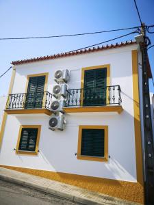 un edificio bianco con persiane verdi e balcone di Refúgio d' Aldeia a Reguengos de Monsaraz