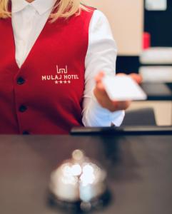 a woman in a red vest holding a remote control at Mulaj Hotel in Tirana