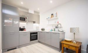 uma cozinha com armários brancos e uma mesa de madeira em Blue Sapphire em Milton Keynes