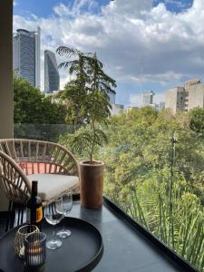 a table with wine glasses on a balcony with a tree at Condesa Cibel in Mexico City