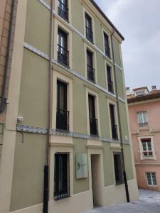 un edificio amarillo con ventanas y una puerta en Hotel Myro, en Gijón