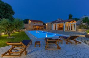 a swimming pool with chairs and a house at Stone Mill House in Vrh