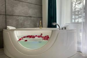 a bathroom with a bath tub with red flowers in it at Arkadiya Sky Jakuzi & MP 24 in Odesa +17 photos