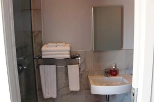 a bathroom with a sink and a shower with towels at Poppy Apartment in Coromandel Town
