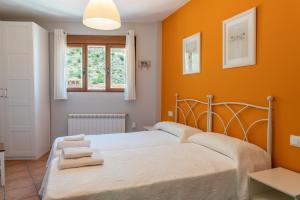 1 dormitorio con 1 cama con paredes de color naranja y ventana en Miralmundo Alojamientos rurales Ayna - CASA RURAL 3 estrellas, en Ayna