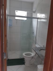 a small bathroom with a toilet and a shower at Apartamento Vila Tropical in Porto Seguro