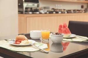 stół z dwoma talerzami jedzenia i szklanką soku pomarańczowego w obiekcie Class Hotel Piracicaba w mieście Piracicaba