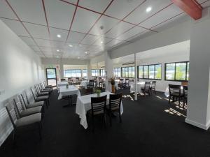 une salle à manger avec des tables blanches, des chaises et des fenêtres dans l'établissement De Lago Resort On Lake Bennett, à Lake Bennett