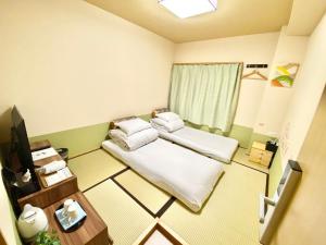 徳島市にあるGuestHouse017徳島個室 飲食街中心 阿波踊り会館7分 文理&徳島大学 アスティとくしま車8分のベッド2台と窓が備わる小さな客室です。