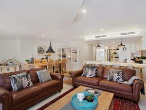 a living room with brown leather couches and a kitchen at The Rocks Resort Apartment GE in Gold Coast