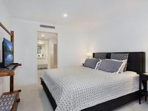 um quarto com uma cama e uma televisão de ecrã plano em The Rocks Resort Apartment GE em Gold Coast