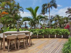 a table and chairs on a deck with palm trees at The Rocks Resort Apartment GE in Gold Coast