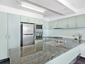 a kitchen with white cabinets and a stainless steel refrigerator at The Rocks Resort Unit 5D in Gold Coast