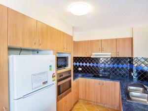 a kitchen with a white refrigerator and wooden cabinets at The Rocks Resort Unit 9J in Gold Coast