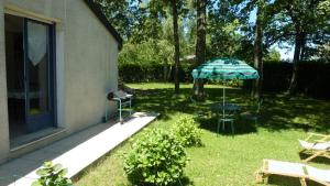 un patio con sombrilla, mesa y sillas en Appartement L'Hivernelle, en Capvern