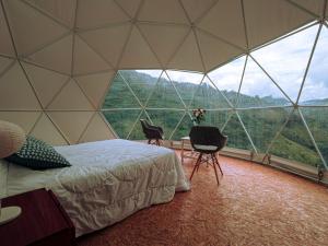 a bedroom in a dome tent with a bed and chairs at VíaLáctea Glamping in Loja