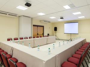 a conference room with a table and chairs and a screen at Rede Andrade Comfort in Natal